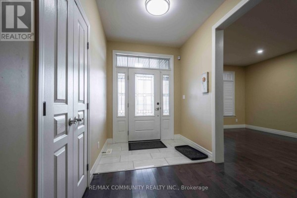 Interior foyer with a white front door, tiled floor, and dark hardwood floors leading further in. - Main - 19 Bevan Drive, Belleville
