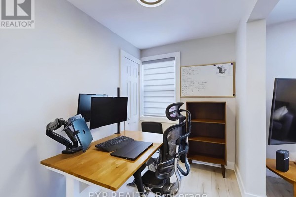 A home office setup with a wooden desk, ergonomic chair, dual monitors, and laptop. - Main - 200 Waterloo Avenue, Guelph