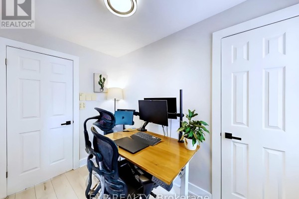 A home office with a desk, two monitors, a laptop, a plant, and multiple doors. - Main - 200 Waterloo Avenue, Guelph