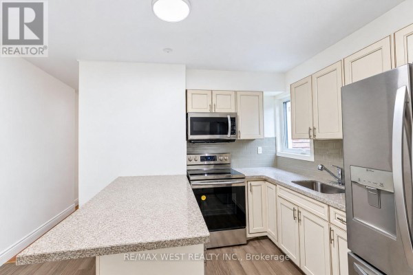 Kitchen with beige cabinets, granite counters, stainless steel appliances, and island. - Main - 203 Islington Avenue, Toronto