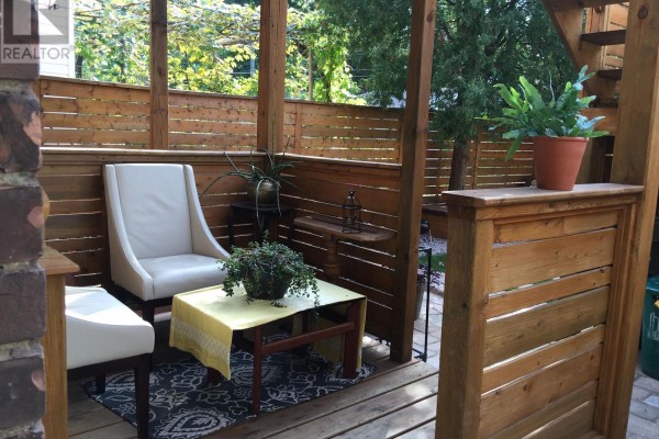 Outdoor seating area with two white chairs and a wooden table on a deck. - Main - 226 Harvie Avenue, Toronto
