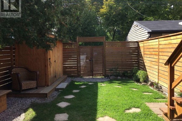 Wooden fence encloses the backyard with a shed and stone path in view. - Main - 226 Harvie Avenue, Toronto