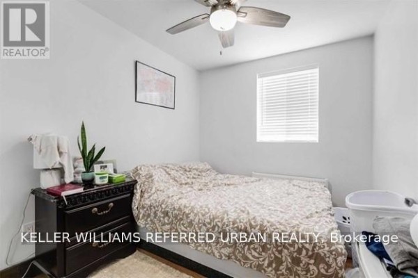 Bedroom with a queen-size bed, dark wood dresser, and a ceiling fan. - Main - 2286 Dufferin Street, Toronto