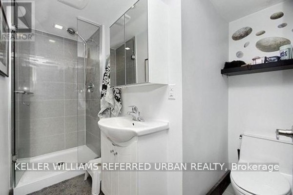 Bathroom with a white sink vanity, toilet, and a tiled shower stall. - Main - 2286 Dufferin Street, Toronto