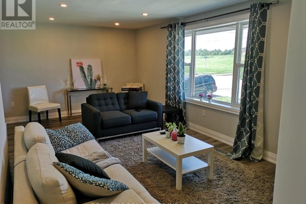 Living room showing a couch, loveseat, coffee table, and a window with a view of the outdoors. - Main - 258 Carson Drive, Hamilton