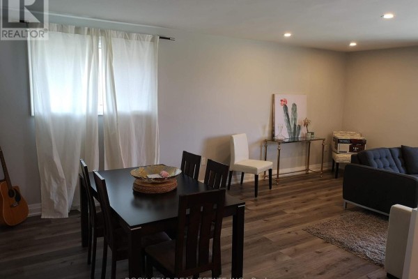 Dining area with a dark wood table and chairs, next to a living room with a couch. - Main - 258 Carson Drive, Hamilton