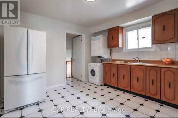 Kitchen with white and black checkered floor, wooden cabinets, refrigerator, and washer/dryer. - Main - 26 Greenleaf Terrace, Toronto