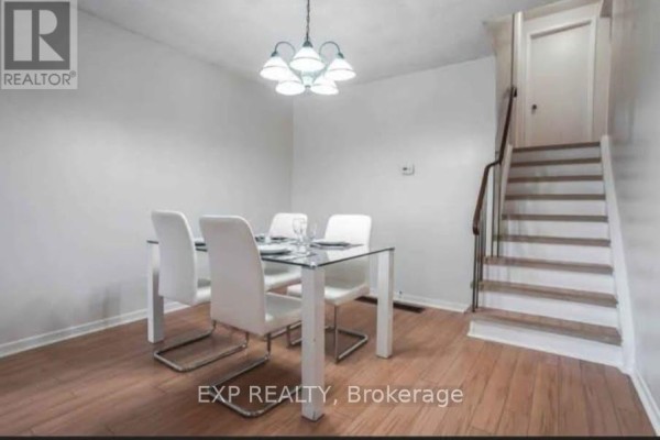 Dining area with a glass-top table, white chairs, hardwood floors, and a staircase. - Main - 26 Greenleaf Terrace, Toronto