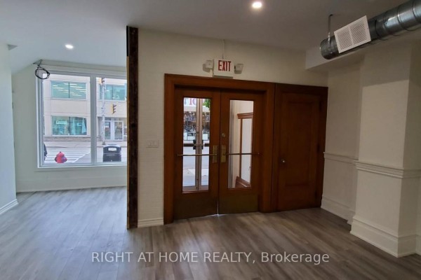 Interior view of a room with light wood floors, double wood doors, and large windows. - Main - 262 Ottawa Street N, Hamilton