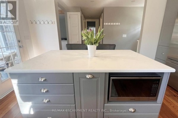 Kitchen island with grey drawers, white quartz countertop, and built-in microwave. - Main - 32 Rodman Street, St  Catharines