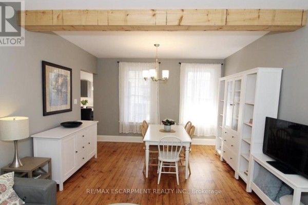 Dining area with a white table, chairs, and white cabinets against grey walls. - Main - 32 Rodman Street, St  Catharines