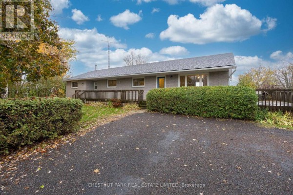 Front exterior of a long, single-story brick house with a driveway and hedges. - Main - 321 Rosebush Road, Quinte West