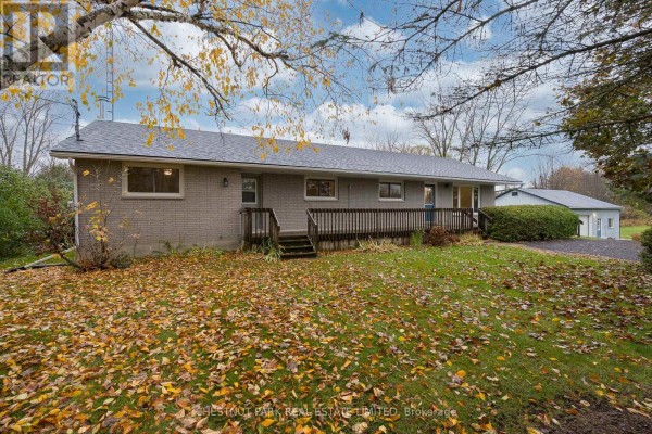 Exterior of a brick house with a lawn covered in fallen autumn leaves and a garage. - Main - 321 Rosebush Road, Quinte West