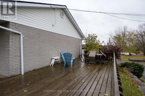 Wooden deck with blue chairs, a table, and brick exterior walls on a cloudy day. - Main - 321 Rosebush Road, Quinte West