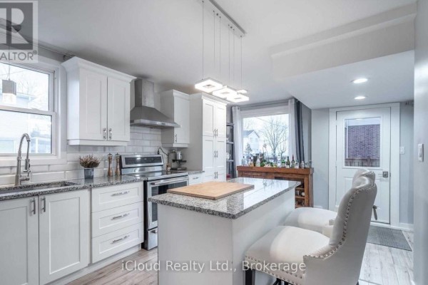 Modern white kitchen with granite countertops, island with bar stools, and stainless steel appliances. - Main - 361 Beach Boulevard W, Hamilton