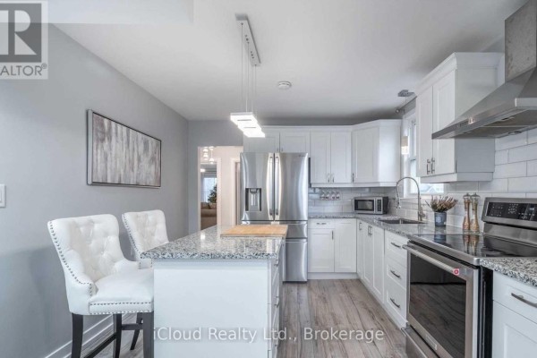 Bright white kitchen with granite countertops, stainless steel refrigerator, and island with bar stools. - Main - 361 Beach Boulevard W, Hamilton