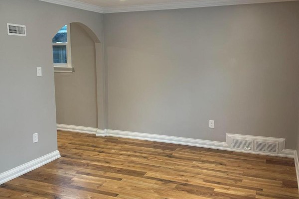 Interior of a room with grey walls, hardwood floors, and an arched doorway. - Main - 394 Whitmore Avenue, Toronto