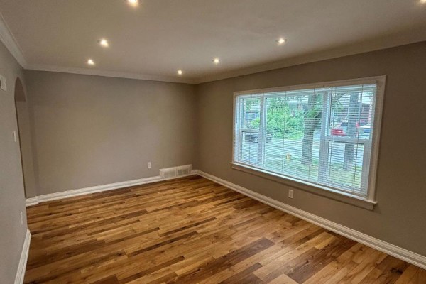 Living room with grey walls, hardwood floors, recessed lighting, and a large window with blinds. - Main - 394 Whitmore Avenue, Toronto