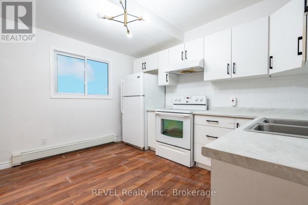 Empty room with hardwood flooring and doorway to kitchen - Main - 4762 Kincaid Place, Niagara Falls