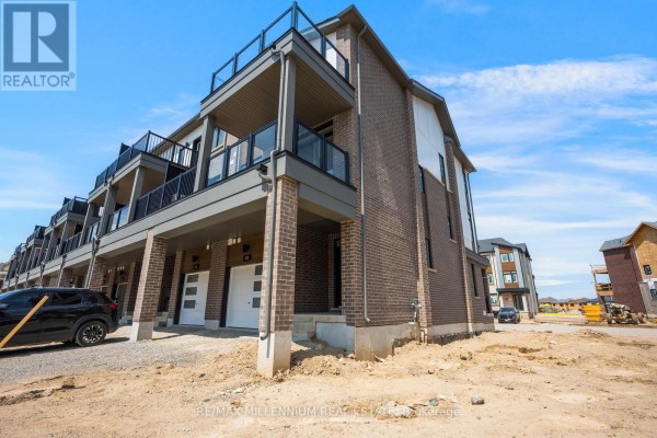 Side view of townhouse complex showing garages, balconies with glass railings, and brick exterior. - Main - 50 Thornbird Crescent, Brampton