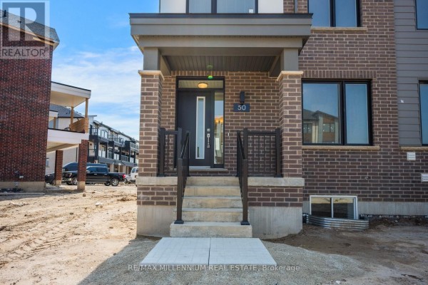 Close-up of a townhouse entrance with a dark door, number 50, brick pillars, and concrete steps. - Main - 50 Thornbird Crescent, Brampton