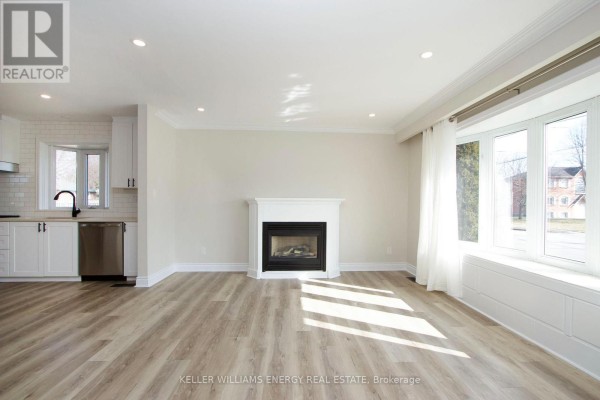 Living room with white fireplace, large bay window, and open view to kitchen area. - Main - 574 Olive Avenue, Oshawa