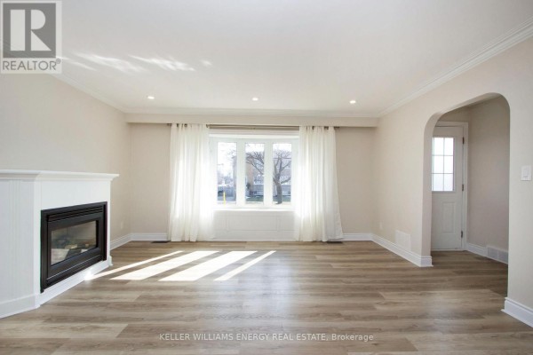 Living room fireplace and white curtains covering a large bay window. - Main - 574 Olive Avenue, Oshawa