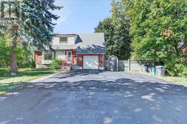 Front exterior of a red brick house with a driveway and green trash bins. - Main - 78 Harold Street, Brampton