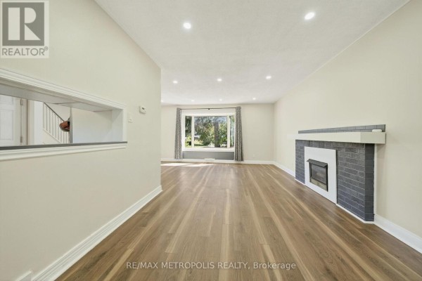 Living room with a fireplace, large picture window, and light wood laminate flooring. - Main - 78 Harold Street, Brampton