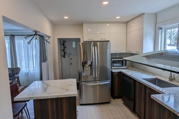 Modern kitchen with stainless steel appliances, white and dark wood cabinets, and a marble island. - Main - 85 Ranstone Gardens, Toronto