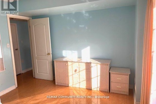 Bedroom with light blue walls, wooden floor, and a light-colored dresser and nightstand. - Main - 88 Wharnsby Drive, Toronto