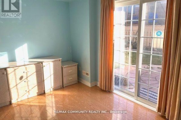 Bedroom with light blue walls, wood floor, and a sliding glass door leading outside. - Main - 88 Wharnsby Drive, Toronto