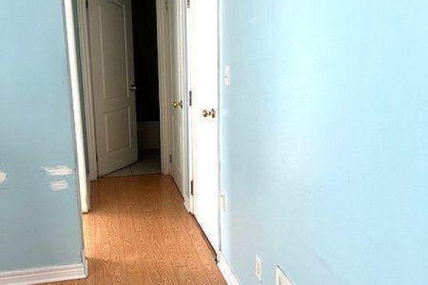 Interior hallway with light blue walls, wood floor, and multiple closed doors. - Main - 88 Wharnsby Drive, Toronto