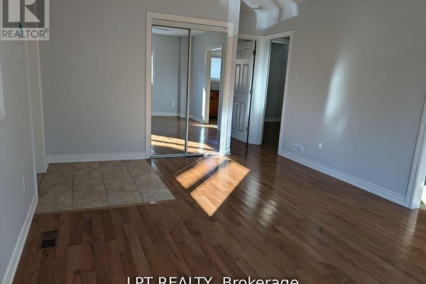 Bedroom with hardwood floors, beige walls, and mirrored closet doors reflecting an open doorway. - Main - 9 Atkinson Avenue, Toronto
