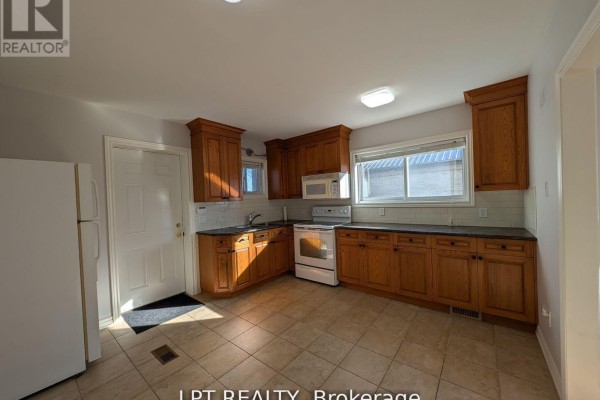 Kitchen with oak cabinets, white appliances, tiled floors, and white subway tile backsplash. - Main - 9 Atkinson Avenue, Toronto