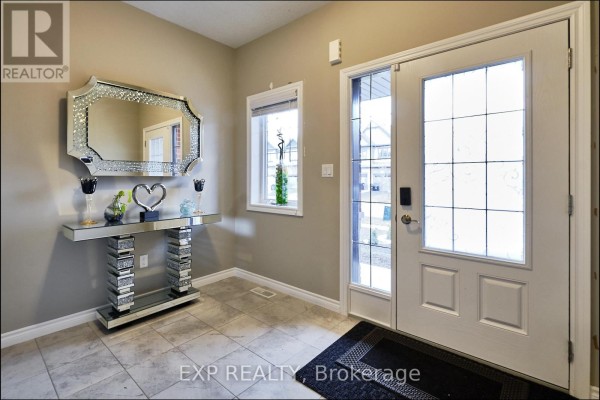 Foyer with a decorative console table, a large mirror, a window, and a front door with glass panels. - Main - 967 Wright Drive, Midland