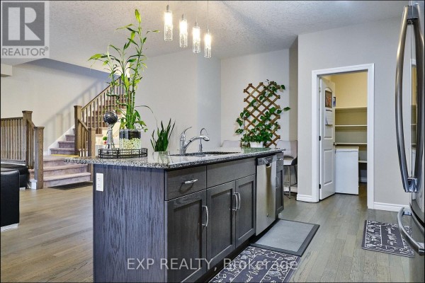Kitchen island with a granite countertop, stainless steel appliances, and a view of the staircase and pantry. - Main - 967 Wright Drive, Midland