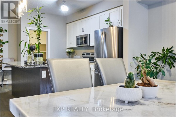 Kitchen with white cabinetry, stainless steel appliances, and a marble-topped dining table with two chairs. - Main - 967 Wright Drive, Midland