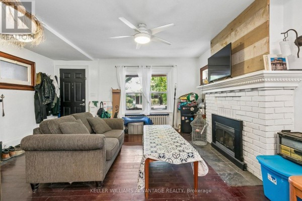Living room with grey striped sofa, coffee table, fireplace, and wood accent wall. - Main & 2nd - 585 Woodbine Avenue, Toronto