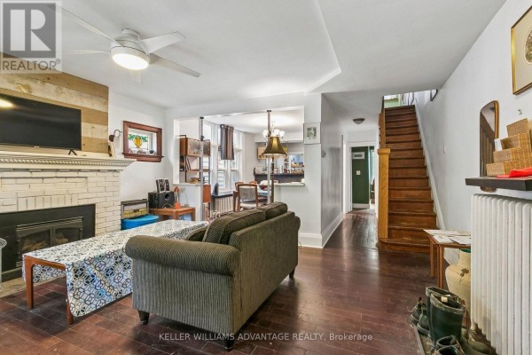 Living room with sofa, fireplace, and view into dining area and staircase. - Main & 2nd - 585 Woodbine Avenue, Toronto