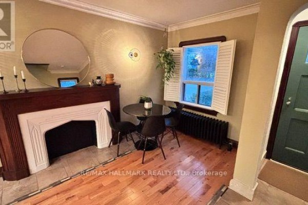 Living room with wood floors, a fireplace, a round dining table, and a window. - Main & 2nd Floors - 457 Mortimer Avenue, Toronto