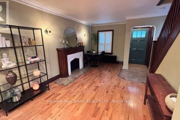 Living and dining area with wood floors, fireplace, dining table, and a shelving unit. - Main & 2nd Floors - 457 Mortimer Avenue, Toronto
