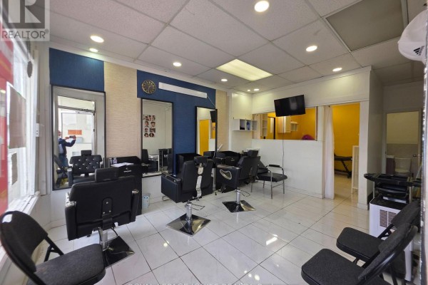 Interior of the hair salon showing multiple black styling chairs, mirrors, and blue accent walls. - Main Floor (front Side) - 2426 Kingston Road, Toronto