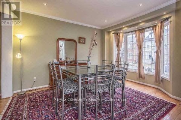 Dining room with a glass-top table, metal chairs, a patterned rug, and a bay window. - Main Floor - 11 Horsetail Street, Markham