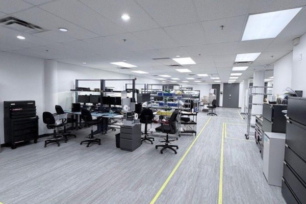 Spacious open-plan office with multiple workstations, chairs, shelving units, and yellow floor markings. - Main Floor - 139 Mulock Avenue, Toronto