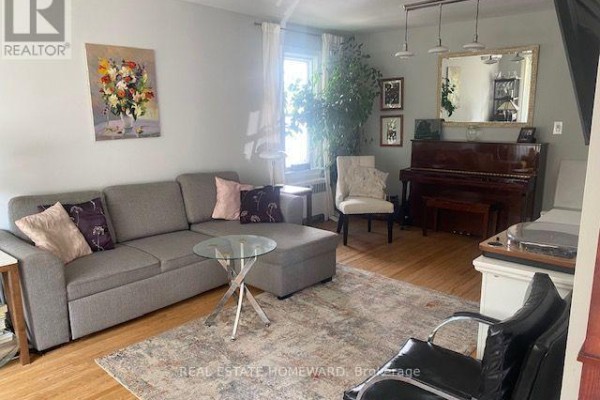 Living room with a grey sectional sofa, an upright piano, and hardwood floors. - Main Floor - 1407 Kenmuir Avenue, Mississauga