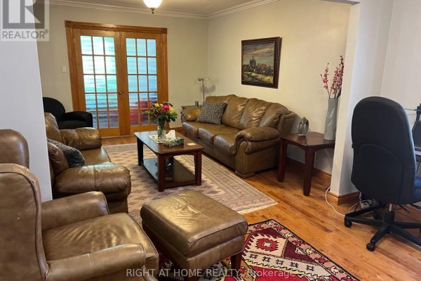 Living room with leather sofas, a patterned rug, hardwood floors, and double glass doors. - Main Floor - 15 Lynnhaven Road, Toronto