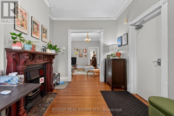 Hallway with light grey walls, hardwood floors, dark wood dresser, and doorway to living area. - Main Floor - 20 Draper Street, Toronto