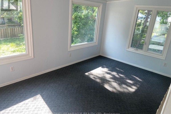 Bedroom with grey carpet, light blue walls, and three windows with outdoor views. - Main Floor - 25 Thornridge Crescent, Kitchener