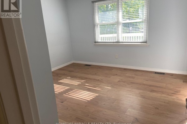 Bedroom with light wood laminate flooring, light blue walls, and a window with blinds. - Main Floor - 25 Thornridge Crescent, Kitchener